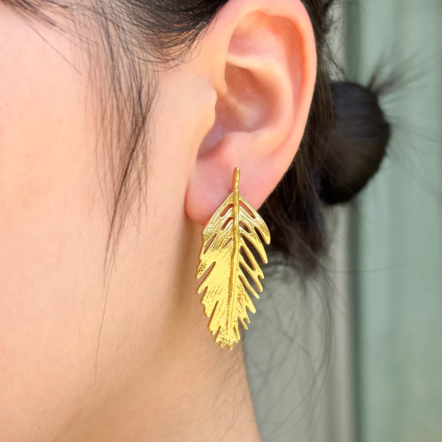 Ajatine gold feather earrings are perfect for adding elegance to a woman's fashionable outfit.