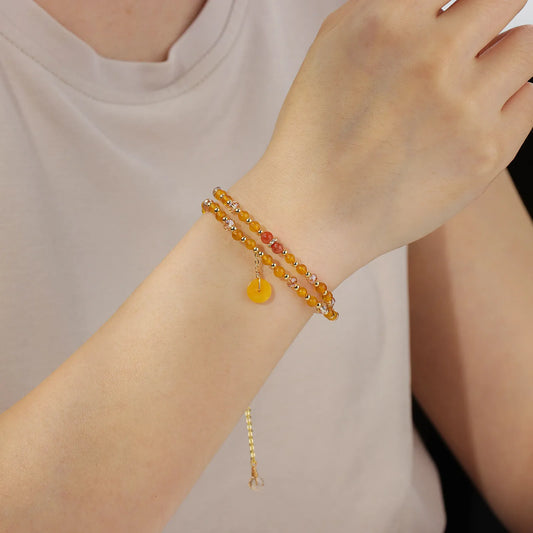 A double - layered beaded bracelet with yellow and light pink beads and a gold - tone disc charm.