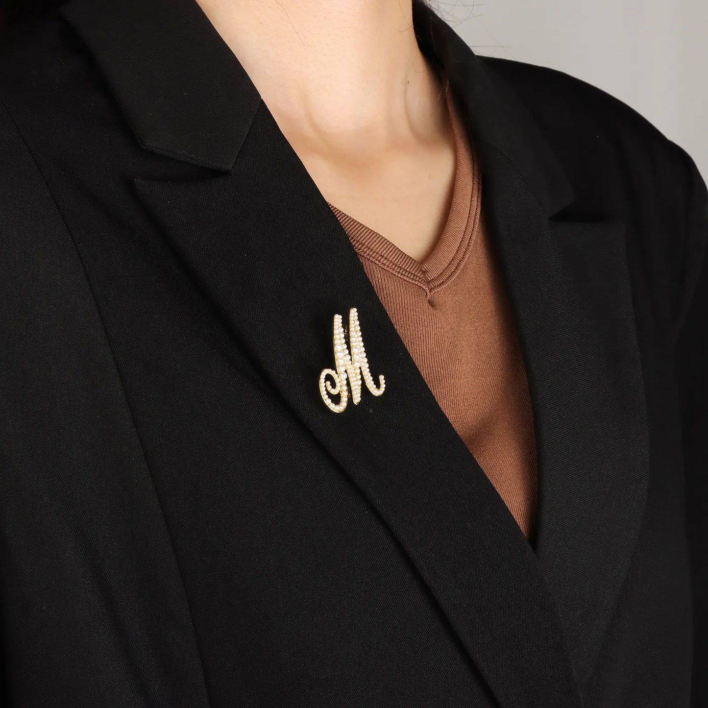 Ajatine gold pearl initial M brooch with elegant design, featuring pearls