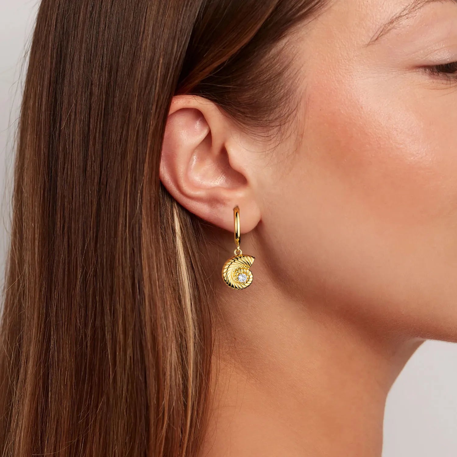 Gold conch dangle earrings with elegant spiral detail