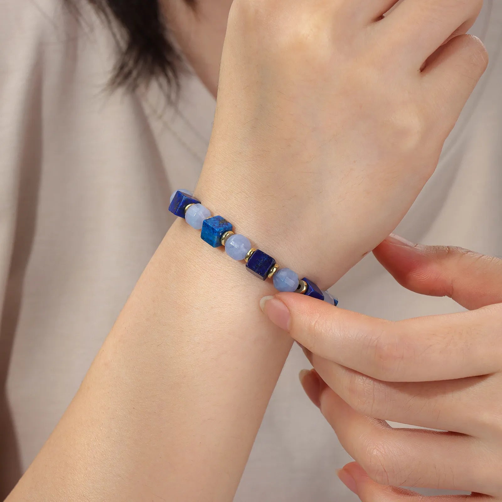 A beaded bracelet made of blue and light blue stone beads with gold accents.