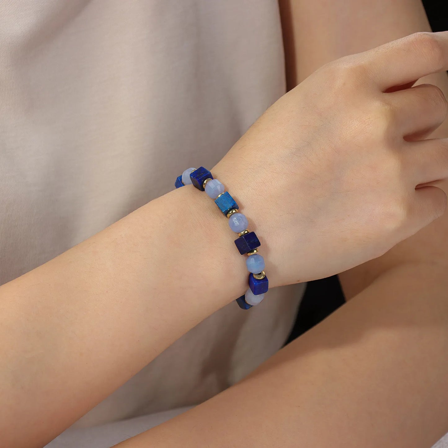 A beaded bracelet made of blue and light blue stone beads with gold accents.