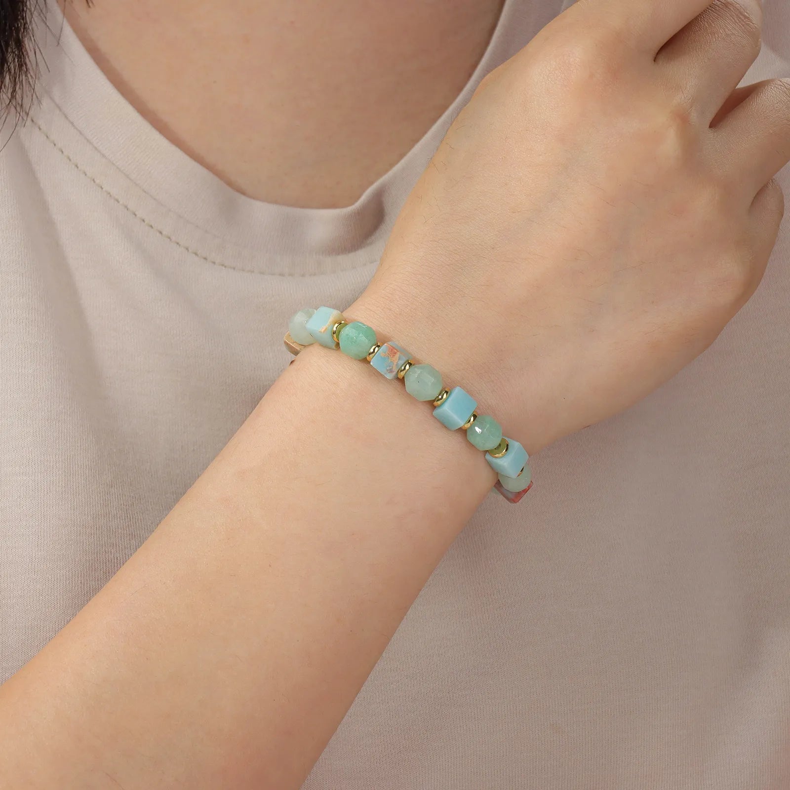 A beaded bracelet made of colorful stone with gold - toned accents.