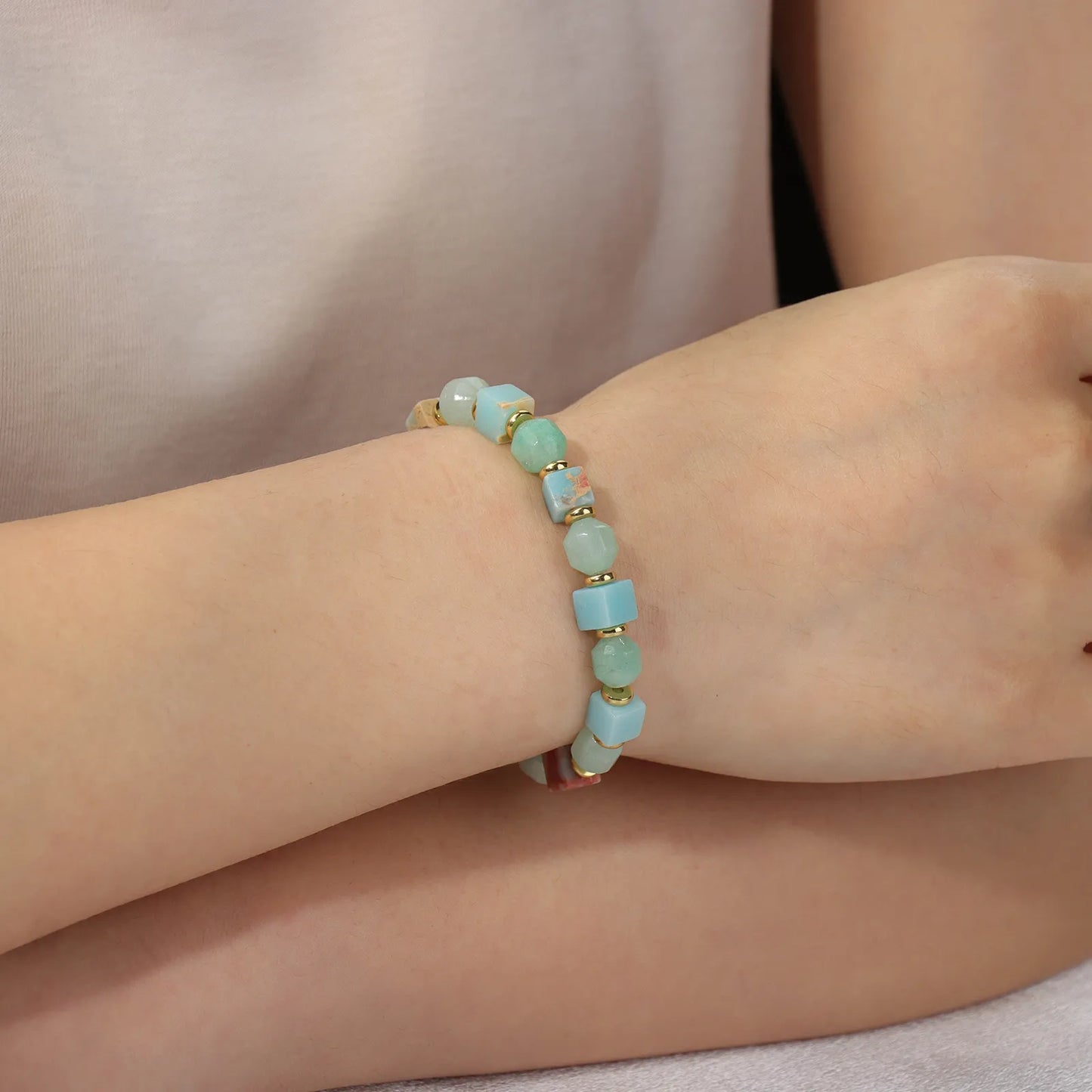 A beaded bracelet made of colorful stone with gold - toned accents.