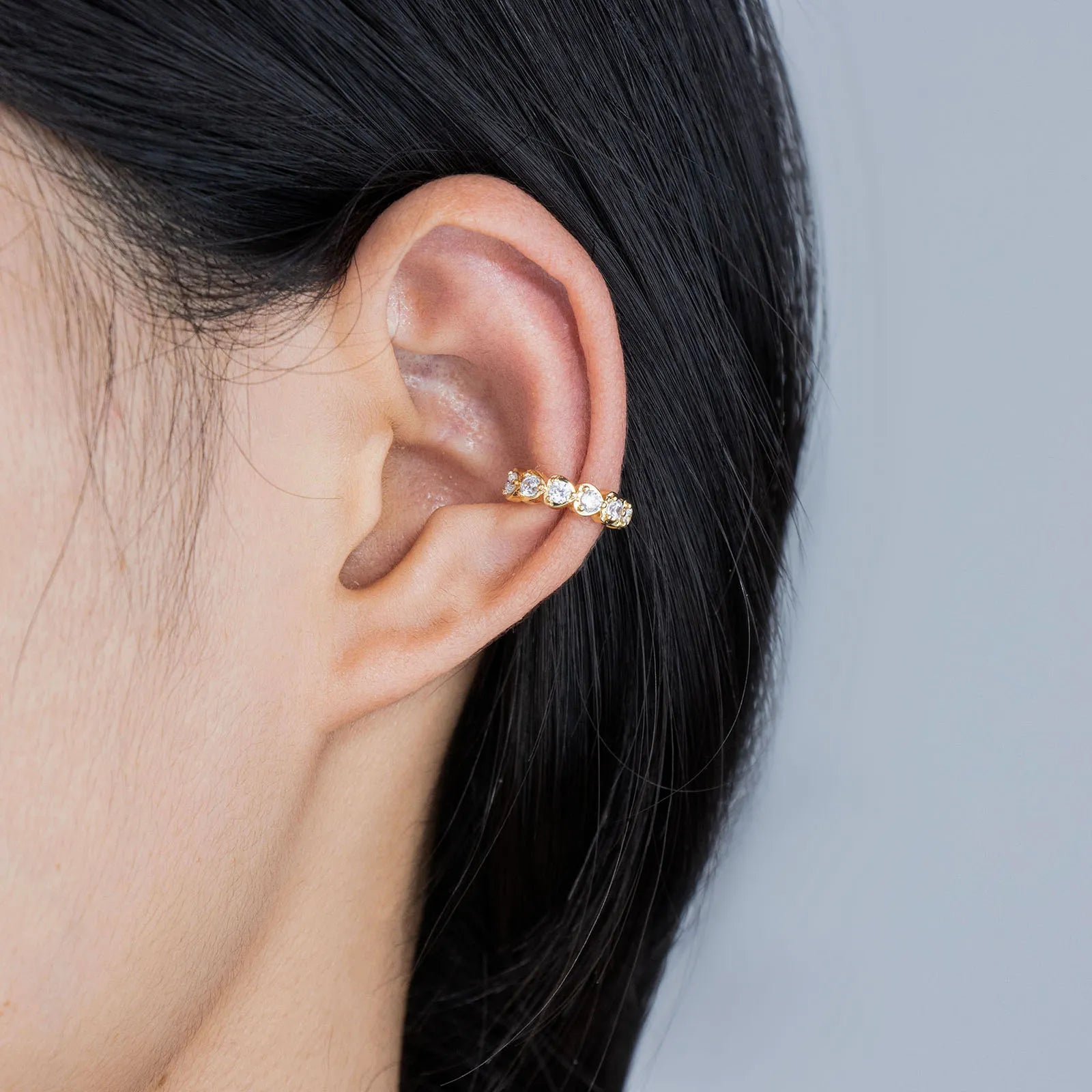 Pair of gold toned ear cuffs with cubic zirconia stones, showcasing a stylish and delicate design