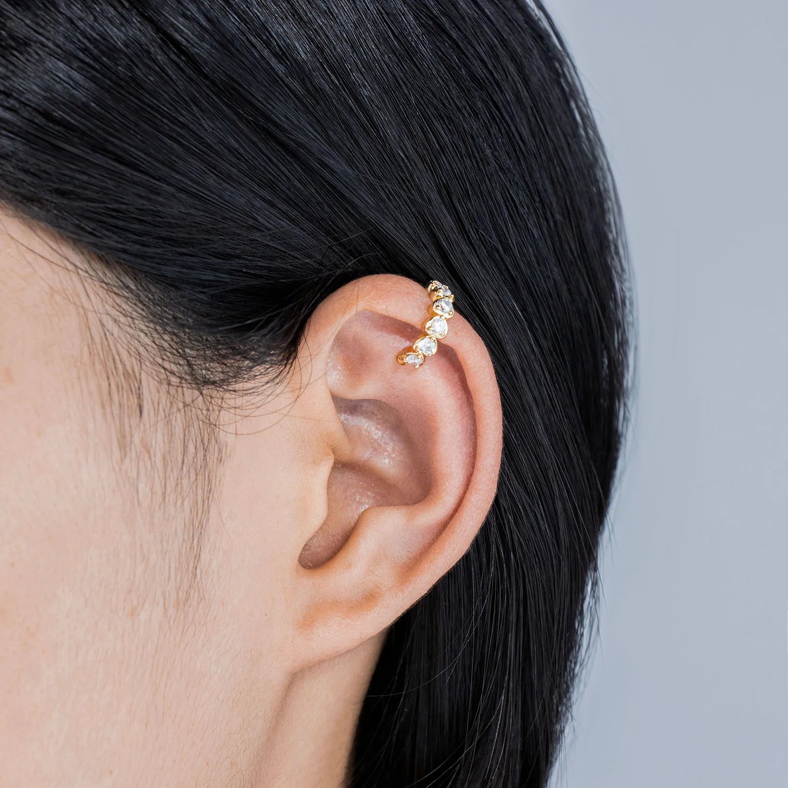 Pair of gold toned ear cuffs with cubic zirconia stones, showcasing a stylish and delicate design