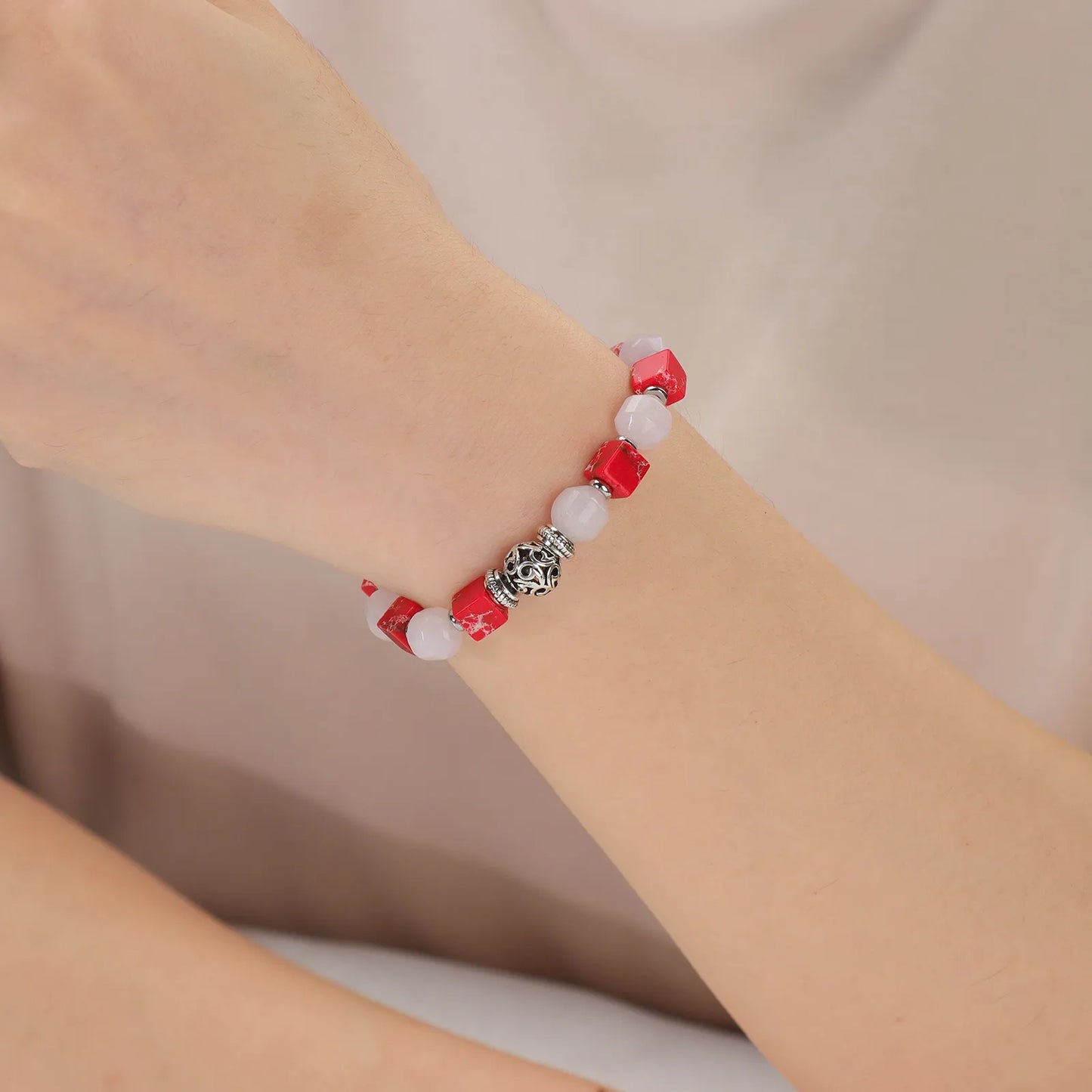A bracelet with pink and red stones and a silver accessories.