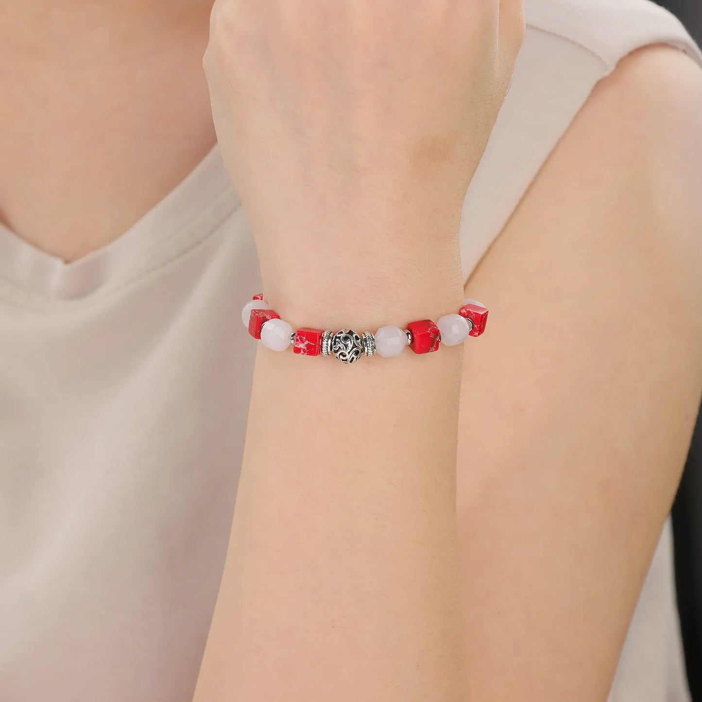 A bracelet with pink and red stones and a silver accessories.