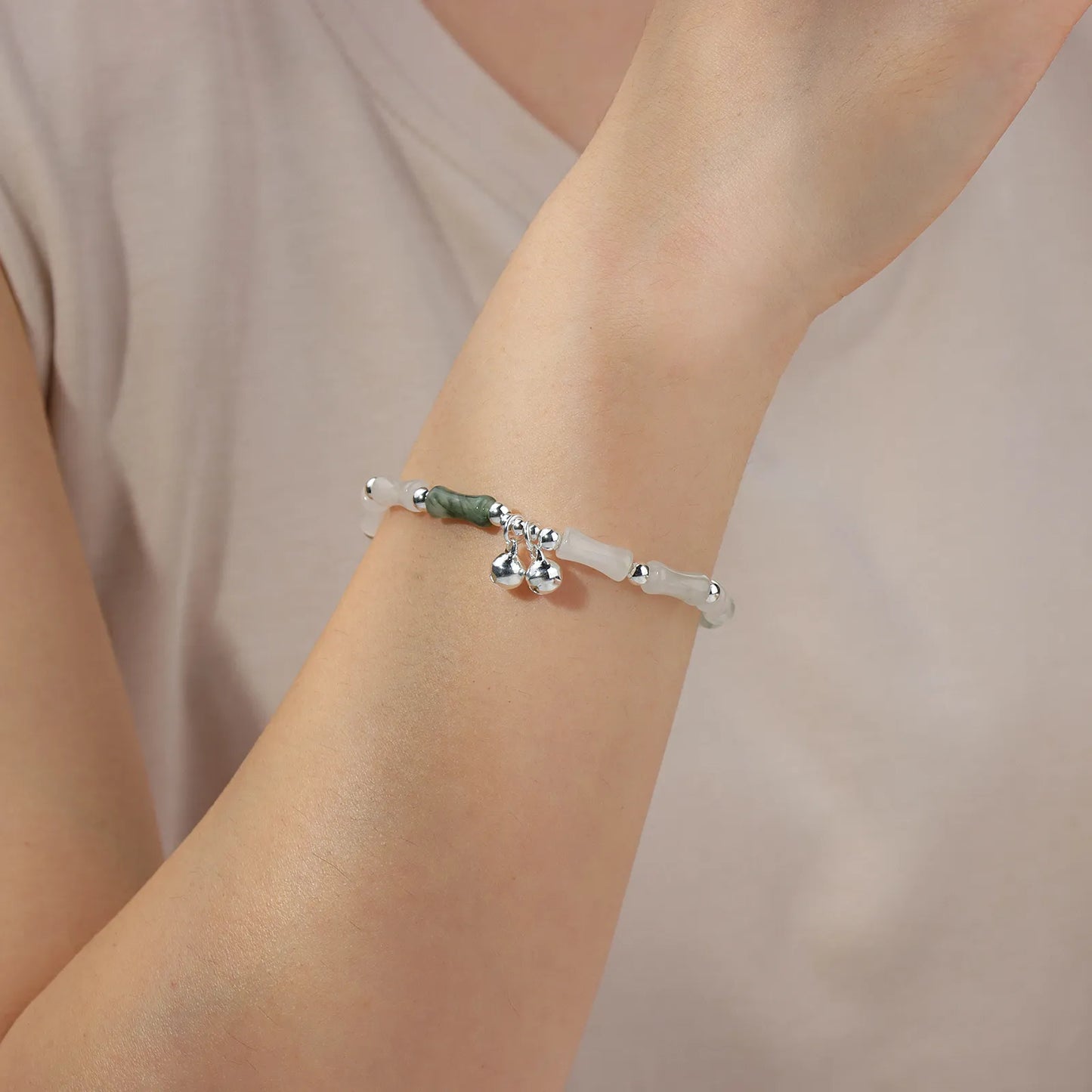 Bead chain bracelet with bamboo - shaped stones and silver bells, showing elegant oriental style.