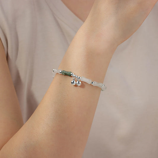 Bead chain bracelet with bamboo - shaped stones and silver bells, showing elegant oriental style.